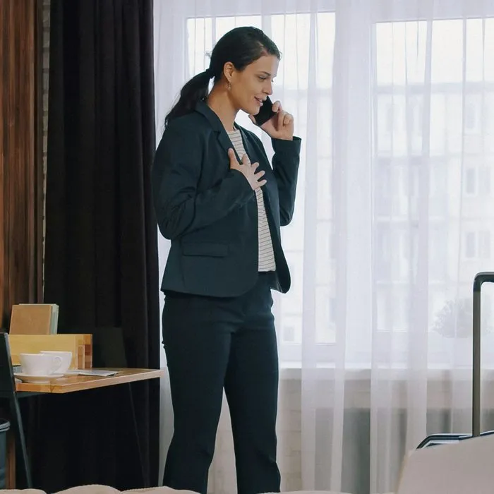 A woman in a suit making a phone call by an office window